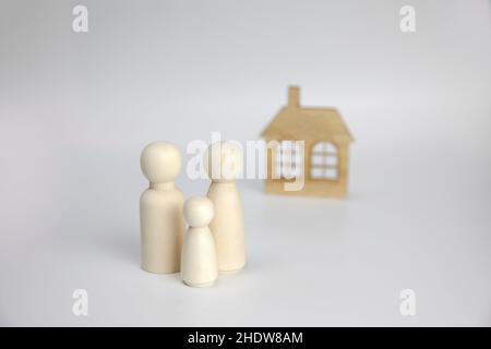 Chiffres de famille sur fond blanc près de la maison.Concept de famille et de maison heureux.Parents et enfants avec espace de copie Banque D'Images