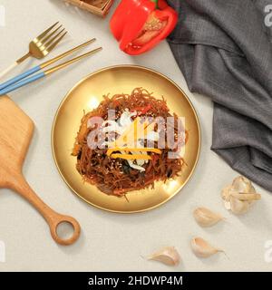 Japchae, Nion de verre coréen Stir Fry sur plaque dorée Banque D'Images