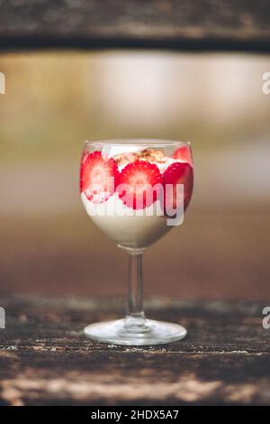 Coupe verticale d'un pudding à la crème fouettée et aux fraises sur une table en bois Banque D'Images