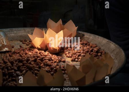 Amandes frites dans le sucre sur une poêle.Amandes en cônes de papier sur le marché de Noël Banque D'Images