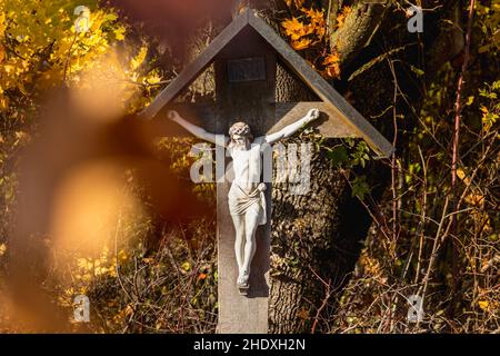 Une croix en Bavière, des feuilles d'automne brunes qui encadrent Jésus Banque D'Images