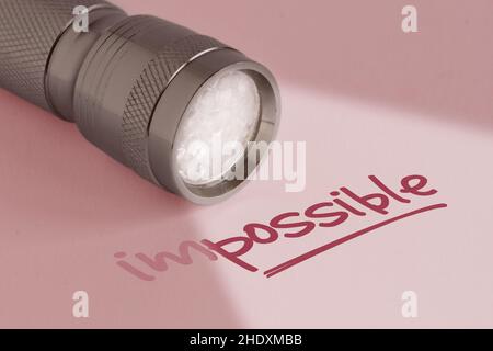 Lampe de poche avec le mot impossible sur fond rose - concept de pensée positive et de changement impossible dans possible Banque D'Images
