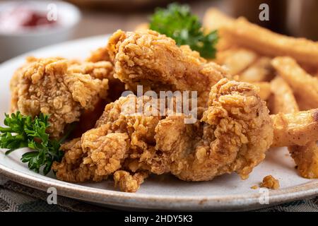 Gros plan sur une assiette de filets de poulet frits et de frites garnies de persil Banque D'Images