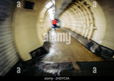 Moody image floue d'une personne vue de derrière dans une veste rouge traversant le Greenwich foot tunnel sous la Tamise, 30th décembre 2021 Banque D'Images