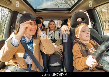 La voiture concept amusant. petit garçon voiture conduite avec des adultes personnes. manque de pilote. voyage. vue de l'intérieur Banque D'Images