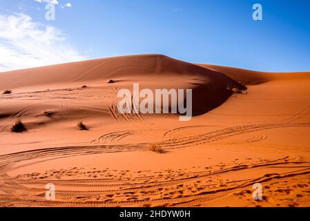 Dunes de sable avec marques de pneus dans le désert le jour ensoleillé d'été contre le ciel Banque D'Images