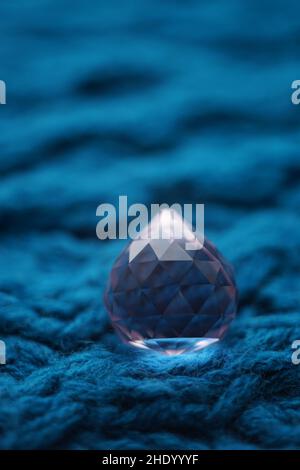 Grand cristal rose sur une table tricotée bleu foncé. Banque D'Images