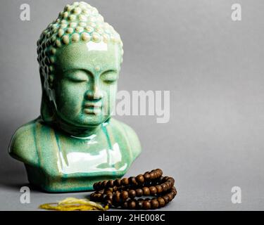 Gros plan d'une figurine de tête de bouddha isolée sur fond gris Banque D'Images