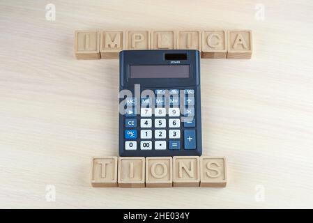Mot implications faites par des cubes en bois et calculatrice.Concept Banque D'Images