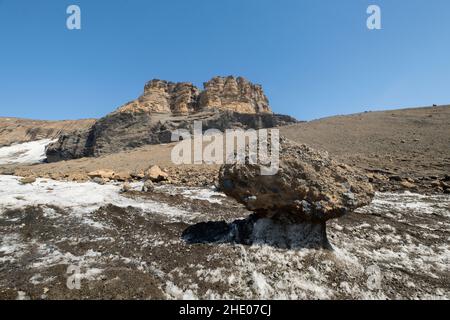 Un rocher est laissé sur un piédestal de glace alors que le glacier de Brown Bluff en Antarctique fond. Banque D'Images
