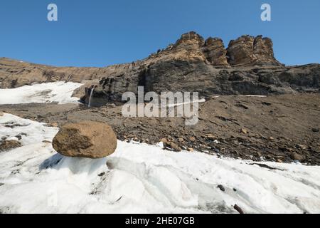 Un rocher est laissé sur un piédestal de glace alors que le glacier de Brown Bluff en Antarctique fond. Banque D'Images