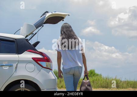 femme asiatique allant en vacances, chargeant leur coffre de voiture avec des valises de voyage Banque D'Images