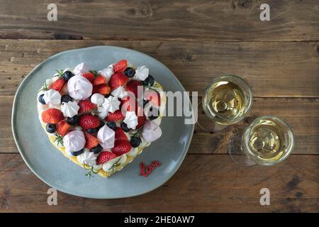 Gâteau en forme de coeur décoré de fruits rouges et de meringue.Arrière-plan rustique en bois.Saint Valentin.Copier l'espace. Banque D'Images