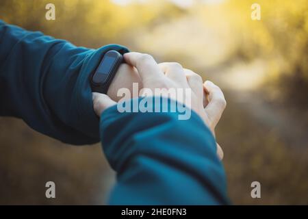 Femme sportive utilisant un tracker d'entraînement ou une montre intelligente entre les entraînements en extérieur. Banque D'Images