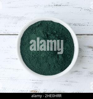 La poudre d'algues spiruline dans un bol sur une table en bois. Banque D'Images