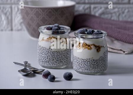 Graines de Chia au yaourt recouvertes de bleuets congelés sur table blanche Banque D'Images