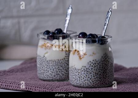 Graines de Chia au yaourt recouvertes de bleuets congelés sur table blanche Banque D'Images