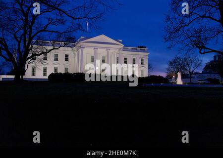 Maison blanche éclairée par des lumières extérieures au crépuscule avec un ciel bleu profond. Bon espace de copie en bas du cadre. Banque D'Images