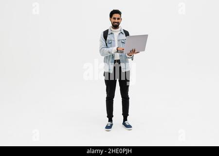 Un beau jeune étudiant en utilisant ordinateur portable et sac à dos de transport isolé sur fond blanc Banque D'Images