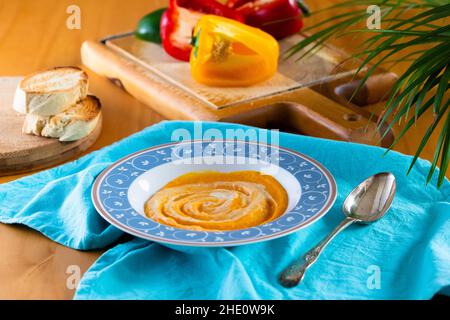 Soupe à la crème au poivron servie dans une assiette bleue Banque D'Images