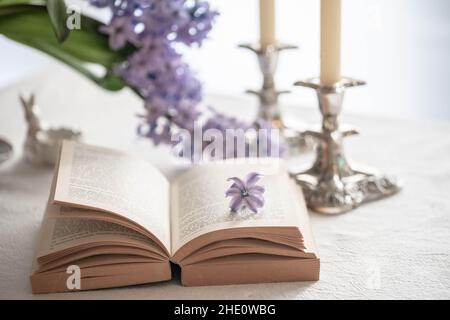 livre ouvert et deux bougies sur une table avec fleurs printanières Banque D'Images