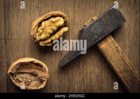 Noyer fissuré par un vieux marteau dans un environnement sombre sur une table en bois.Photo de haute qualité Banque D'Images