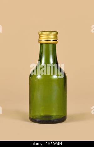 Une bouteille vide en verre vert sur fond beige Banque D'Images