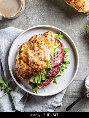 Sandwich croissant frais avec jambon et feuille de salade avec café sur fond texturé, vue du dessus Banque D'Images