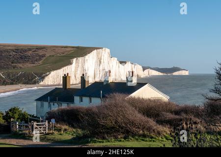 Chalets avec garde-côtes en premier plan. Au loin se trouvent les falaises de craie emblématiques de Seven Sisters à Seaford, sur la côte sud de l'Angleterre au Royaume-Uni. Banque D'Images