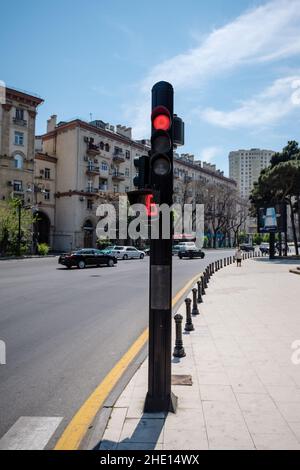 Bakou, Azerbaïdjan - 1 mai 2019 : rue centrale de Bakou avec feu rouge et voitures roulant rapidement sur l'autoroute urbaine asphaltée avec architecture soviétique en arrière-plan Banque D'Images