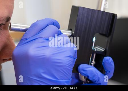 Scientifique vérifiant l'état de l'aiguille du nébuliseur du système LC MS qTOF à l'aide du dispositif de réglage et de la loupe. Banque D'Images