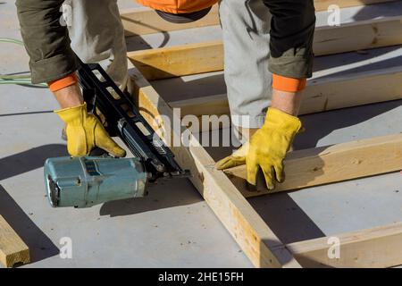 Constructeur à l'intérieur de bois homme en clouant des poutres en bois travaux de construction à l'aide d'un marteau pneumatique Banque D'Images