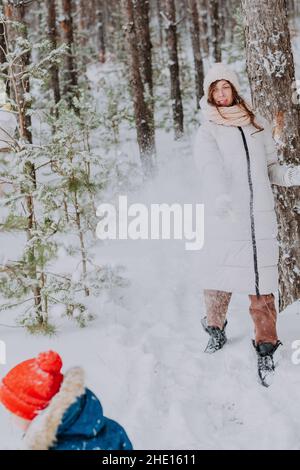 maman et fils jouent des boules de neige dans la forêt d'hiver.Maman marche avec son fils dans une chute de neige dans la forêt.Joyeuses vacances d'hiver avec la neige.Promenades en hiver Banque D'Images