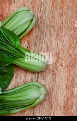 Bok choy brut fraîchement lavé sur une planche à découper en bois Banque D'Images