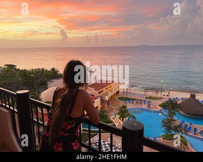 Cozumel, Quintana Roo, Mexique - 17 décembre 2021 : une femme regarde un magnifique coucher de soleil à travers la fenêtre ouverte.Coucher de soleil sur la mer des Caraïbes Banque D'Images