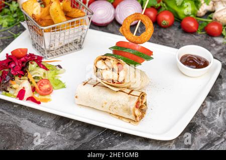 Enveloppement de poulet avec frites et salade sur une table en marbre Banque D'Images