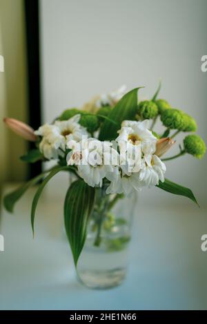 Bouquet de fleurs flétries dans un vase sur un rebord de fenêtre. Banque D'Images