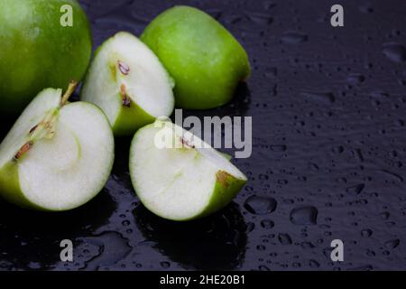 pommes granny smith vertes, fraîches et croustillantes, sur une surface noire avec des gouttelettes d'eau Banque D'Images