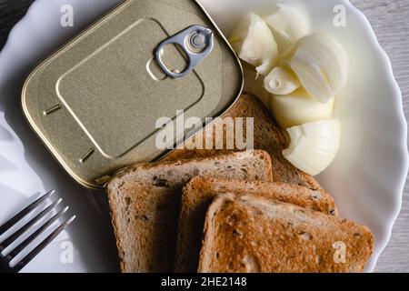 Gros plan sur l'assiette avec pain grillé oignon haché et boîte avec sardines en conserve nourriture de poisson jeûne concept Banque D'Images