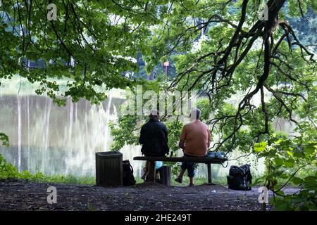 Un homme et une femme sont assis sur un banc près de la rive de l'Étang Rouge dans le parc Izmaylovsky Banque D'Images