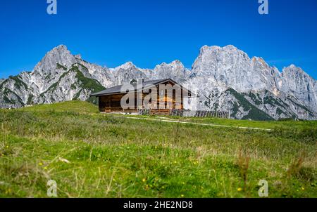 Prairie alpine verte avec cabane en bois devant les impressionnants sommets de montagne, Salzbourg, Autriche, Europe Banque D'Images