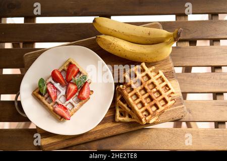 Gaufres avec fraises, bananes et miel. Banque D'Images