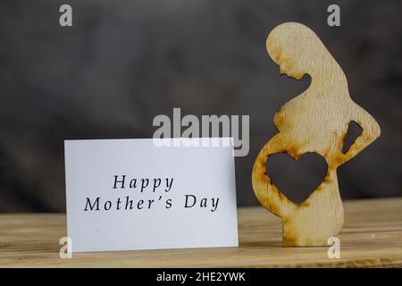 Femme enceinte en bois et coeur, concept de la fête des mères heureuse Banque D'Images