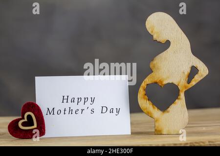 Femme enceinte en bois et coeur, concept de la fête des mères heureuse Banque D'Images