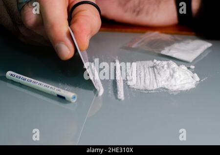 L'homme fractionne la cocaïne en bandes et puis en ronflements.Concept de narcotiques. Banque D'Images