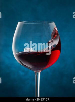 Bateau en papier flottant dans un verre de vin rouge avec une vague Banque D'Images