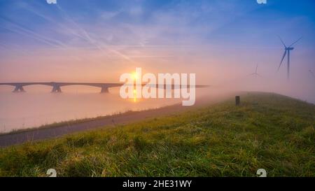 Long pont sur l'eau douce et vivivivivivivivile allant à l'infini au-dessus de l'océan magnifique sous le magnifique ciel coloré de Zeeland, aux pays-Bas Banque D'Images