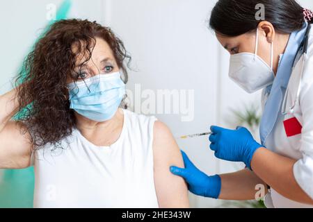 Une travailleuse de la santé vaccine une femme portant un masque.Concept de vaccination chez les personnes âgées. Banque D'Images