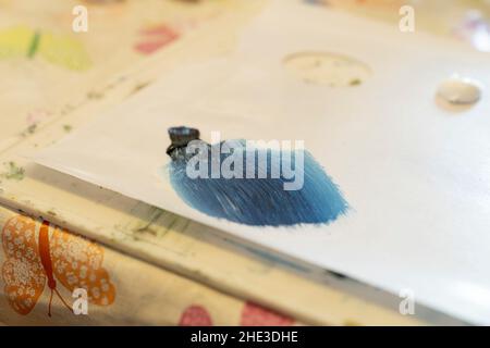 Sur une palette, grassez des traits de pinceau mélangés de peinture bleue noire et blanche Banque D'Images