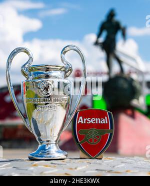 14 juin 2021, Londres, Royaume-Uni.Emblème du club de football Arsenal F.C. et coupe de la Ligue des champions de l'UEFA sur fond de stade moderne. Banque D'Images